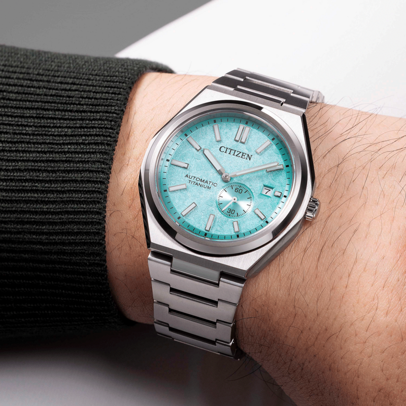 Citizen watch on wrist, turquoise face, automatic titanium, silver bracelet, close-up